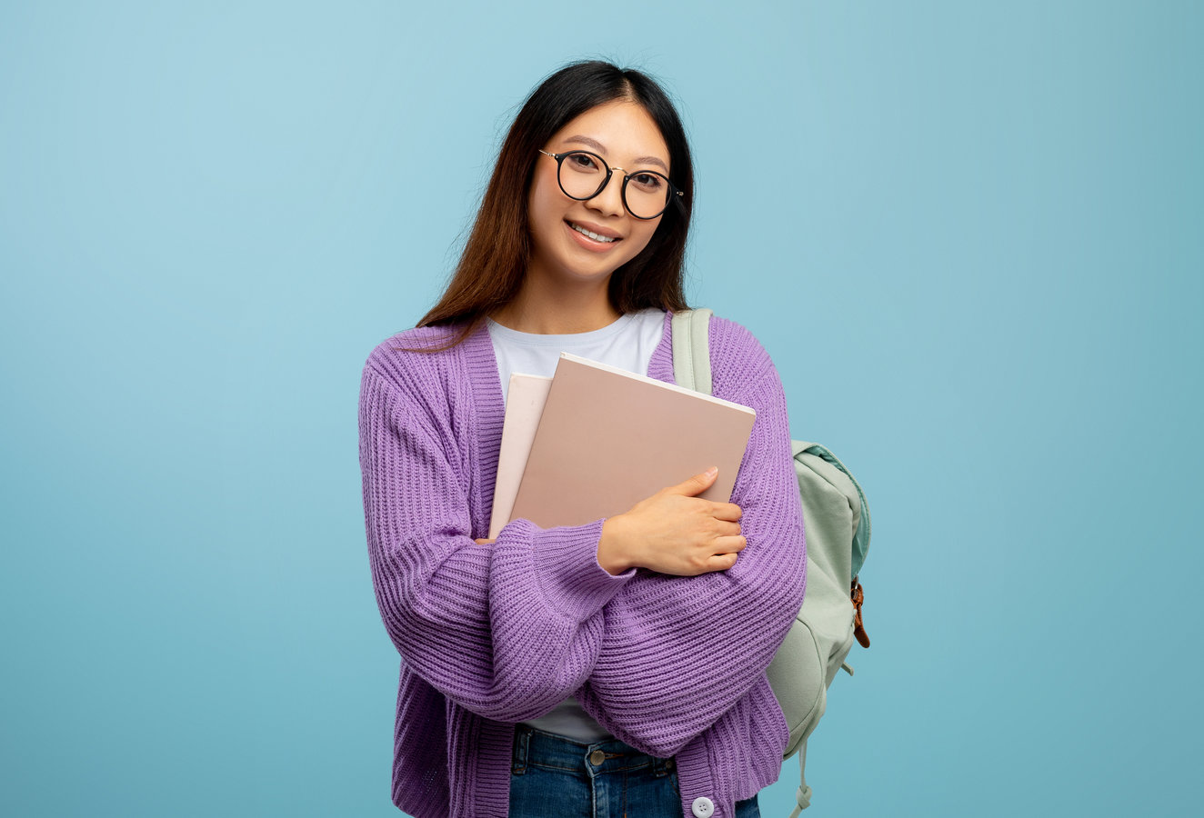 Student holding books and a backpack